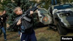 Хлопчик з автоматом Калашнікова у м.Соледар, 27 вересня 2014 року. Діти перебувають під наглядом дорослих, тримаючи зброю.