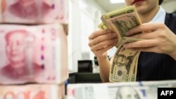 资料照:中国江苏南通一家银行的工作人员正在人民币旁点数美元。(2019年8月6日)