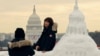 中国游客与美国国会大厦雪雕合影,背景是真实的国会大厦,上面装饰着美国当选总统唐纳德·特朗普即将就职的旗帜。(2025年1月13日)