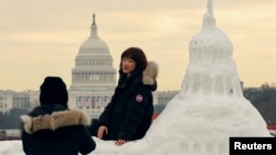 中国游客与美国国会大厦雪雕合影,背景是真实的国会大厦,上面装饰着美国当选总统唐纳德·特朗普即将就职的旗帜。(2025年1月13日)