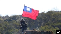 资料照:一名台湾士兵手举台湾旗帜参加新竹举行的军演模拟反击中国军队攻台。(2021年1月19日)