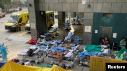 2022年2月16日在香港爆发新冠病毒后,戴着口罩的患者躺在医院外的临时治疗区的床上