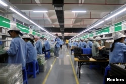 资料照:中国广东东莞一家生产移动游戏控制器的工厂工人在生产线上工作。(2021年12月7日)