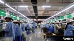 中国广东东莞的工人为一家美国公司的RiotPWR移动游戏控制器在生产线上工作。(2021年12月7日)