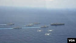 4月28日在冲绳附近海域,日本两艘军舰和两架F15战机参加美国核航母“卡尔·文森”号为首的美军战舰群和航母搭载机联合军演时的布阵航行、飞行环节(日本航空自卫队提供)