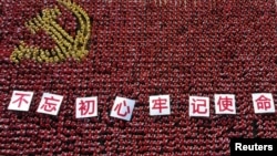 中国浙江省金华市的中共党员手举“不忘初心牢记使命”的标语牌组成中共党旗图案的阵仗。(2019年6月28日)