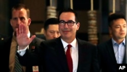 美国财政部长姆努钦在北京与中国官员会谈后回到酒店时向记者挥手致意。(2018年5月3日)