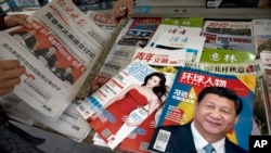 北京报摊上的报纸刊物,其中《环球人物》杂志的封面上有习近平照片和《习近平 中国强起来》的标题,还有报道中共十九大修改党章消息的北京晚报,也有以影视明星范冰冰为封面的《知音》杂志。(2017年10月21日)