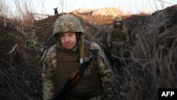 Servicemen of Ukrainian Military Forces walk along tranches on their position on the front line with Russia backed separatists, near Novognativka village, Donetsk region, Feb. 21, 2022.
