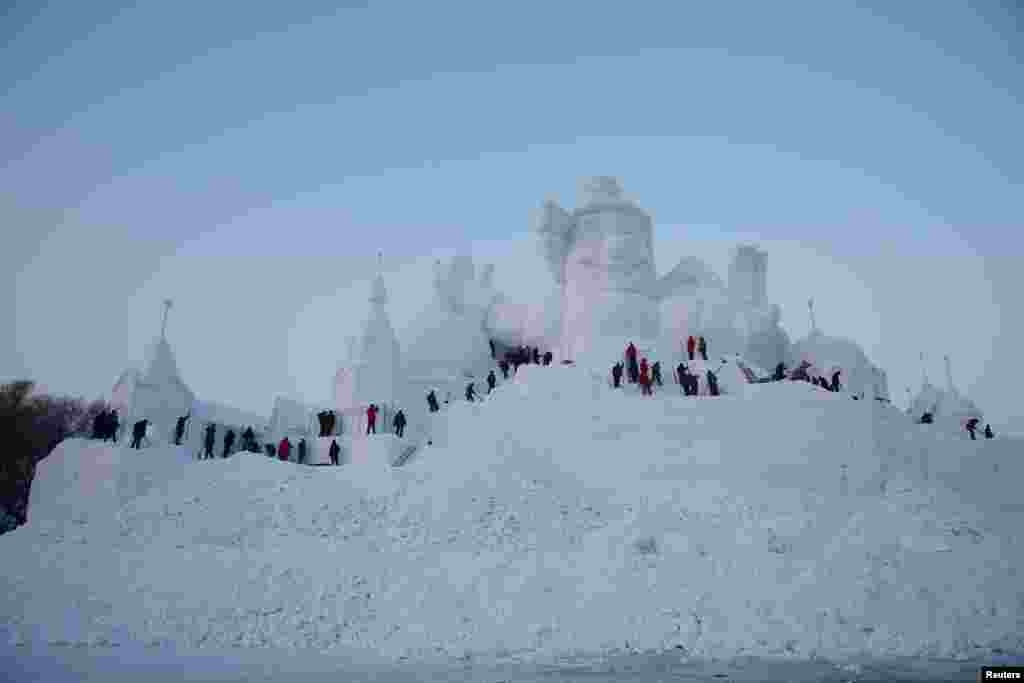 哈尔滨国际冰雪节的雪雕,艺术家和工人正在雕刻(2016年12月17日)