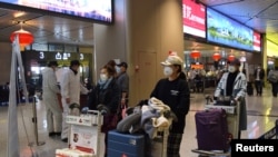 中国黑龙江省会哈尔滨机场的旅客为防疫戴着口罩。(2020年4月11日)