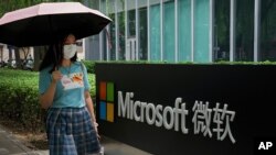 资料照片:一名戴口罩防新冠传染的女士走过微软公司北京一分枝机构。(2021年7月20日)