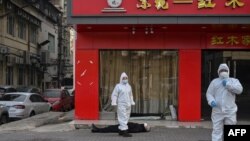 身穿防护服的中国卫生官员在检查一名在武汉一所医院附近倒地死亡的老年男子的家。(2020年1月30日)