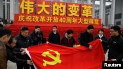 资料照:在纪念中国改革开放40周年的展览会前人们展开一面中共党旗。(2018年11月14日)