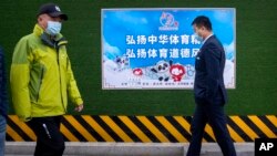 2021年12月8日,行人在北京走过一张宣传2022年冬季奥运会的海报。(美联社照片)
