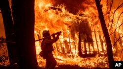 Пожежник гасить палаючий будинок у Каліфорнії. Пожежі в цій місцевості часто є наслідком екстремально гарячої температури повітря.