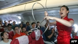 中国东方航空公司的空姐在客机上为乘客表演助兴(2007年9月26日)。