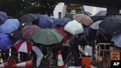 形成路障阻挡香港道路的抗议者躲在遮阳伞后面。(美联社2019年10月4日)
