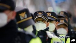 戴口罩的韩国警察在首尔的一个集会上维持秩序 (2月22日)