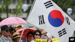 韩国民众手举标语牌和国旗集会支持在韩国部署萨德导弹防御系统(2016年7月18日)