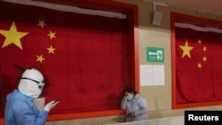 身穿防护服的医护人员在武汉的一所方舱医院里安慰一名病患。(2020年2月27日)