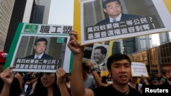 香港民主示威者举着香港特首梁振英像和质问他的口号游行(2014年10月22日)