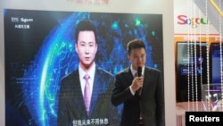在中国乌镇国际互联网大会上,新华社新闻主播邱浩站在以他为原型的人工智能技术合成的新闻主播播放新闻的屏幕前(2018年11月7日)