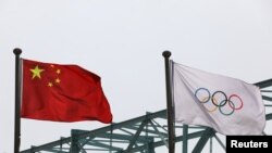 中国国旗和奥运旗帜在北京冬奥组委会外飘扬(路透社2021年3月30日)