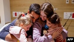 TOPSHOT - An image distributed by the Schneider Children Medical Centre shows Yoni Asher being reunited with his children Aviv, 2.5 years old, her sister Raz, 4.5 years old, and his wife Doron, on November 25, a day after they were released by Hamas in a