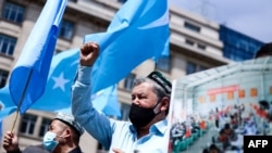 FILE - Demonstrators from the Uyghur community gesture as they take part in a protest near the Belgium parliament in Brussels, July 8, 2021.