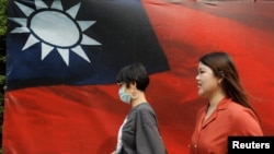 人们从台北街头的台湾旗帜旁走过。(2020年8月10日)