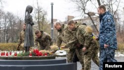 Українські військовослужбовці кладуть колоски до пам’ятника жертвам Голодомору 1932-33 років. Ukrainian Presidential Press Service/Handout via REUTERS