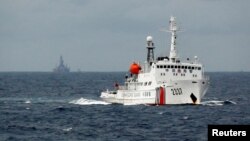 资料照:一艘中国海警船在南中国海上的一座中国海上钻井平台旁驶过。(2014年6月13日)