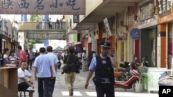 在最近发生袭击的地点附近,8月2日一名巡逻的警察喀什的大街上用手机打电话