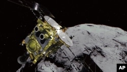 资料照:日本宇宙航空研究开发机构提供的电脑图像显示一颗小行星及“隼鸟2号”小行星探测器。