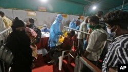 အိန္ဒိယနိုင်ငံ Ahmedabad မြို့မှာ ဘူတာရုံတခုမှာ COVID-19 စစ်ဆေးပေးနေတဲ့မြင်ကွင်း။ (စက်တင်ဘာ ၁၈၊ ၂၀၂၀)