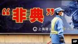 2002-2003年期间中国爆发传染性非典型肺炎(SARS)。一名工作人员戴着口罩走过上海一个对抗“非典”的巨幅广告。2003年资料照。