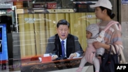2019年1月2日,台湾新北市的一位母亲带着孩子经过一台电视,屏幕上显示中国领导人习近平就台湾问题发表讲话。