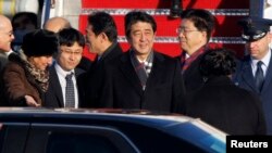 2013年2月21日,日本首相安倍晋三(中)抵达华盛顿附近安德鲁斯空军基地,美国首席礼宾官卡普丽奇娅•马歇尔(左)到机场迎接。