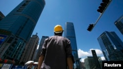 2009年7月16日,一名建筑工人在深圳商业区过马路。(路透社照片)