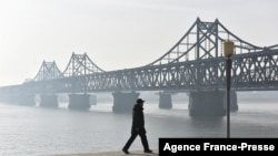 资料照:2019年2月22日,在中国东北辽宁省的丹东市,一名男子走在横跨中朝之间鸭绿江的友谊桥附近。(法新社)