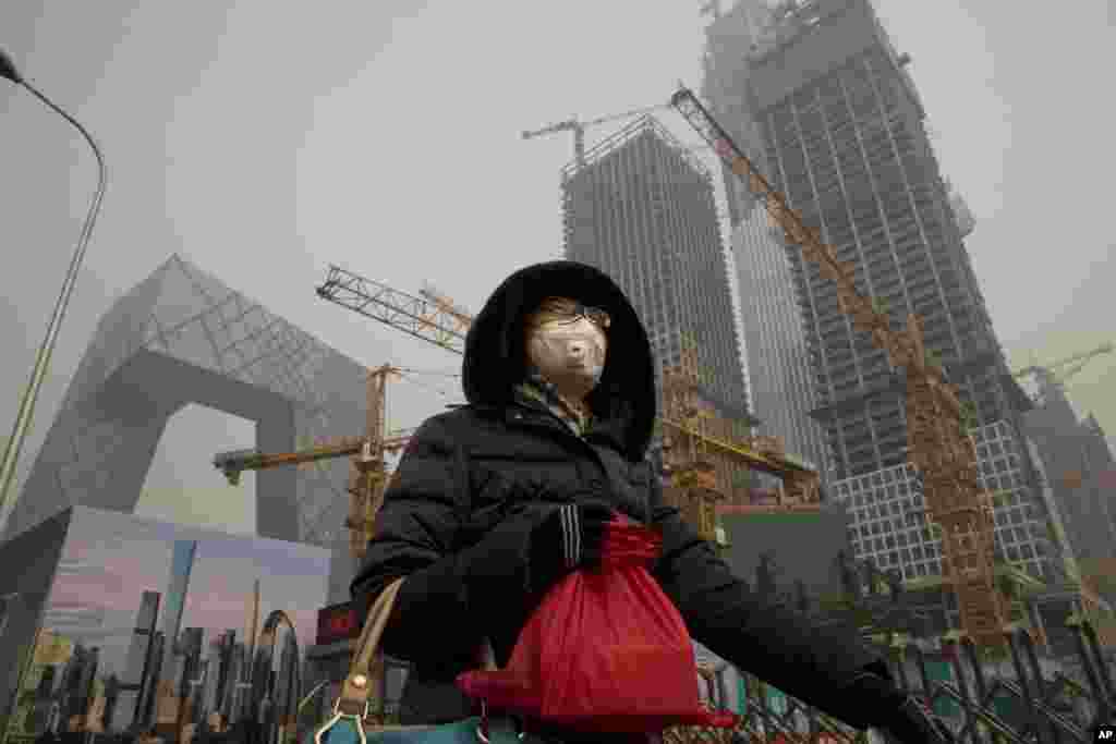 2017年1月6日,在雾霾中,有人戴口罩在北京中央商务区的央视大楼旁边的施工工地走过