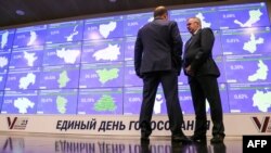 Двоє чоловіків перед інформаційним екраном в Центральній виборчій комісії в Москві, 8 вересня 2023 року. (Photo by AFP)