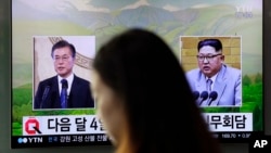 一名女子走过韩国首尔火车站正在播放韩国总统文在寅(左)和朝鲜领导人金正恩画面的电视屏幕。(2018年3月29日)