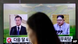 一名女子走过韩国首尔火车站正在播放韩国总统文在寅(左)和朝鲜领导人金正恩画面的电视屏幕。(2018年3月29日)