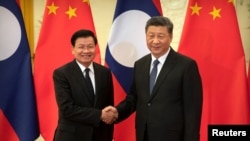资料照片-老挝总理西苏里和中国领导人习近平在北京人民大会堂会面握手。(2020年1月6日)