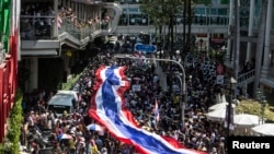 2014年1月13日,泰国反政府抗议者打着巨幅国旗游行走过曼谷市中心购物区。