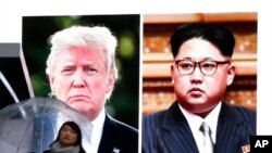 一名女子走过东京街头正在播放朝鲜领导人金正恩与美国总统川普的相关电视新闻的巨型屏幕。(2018年3月9日)
