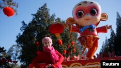 一名女子在北京地坛公园前为迎接中国新年猴年到来树立的猴像前留影 (2016年2月)