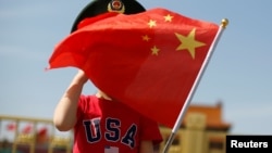 一名站在北京天安门广场的小男孩身穿美国T恤手拿中国国旗。(2019年5月7日)